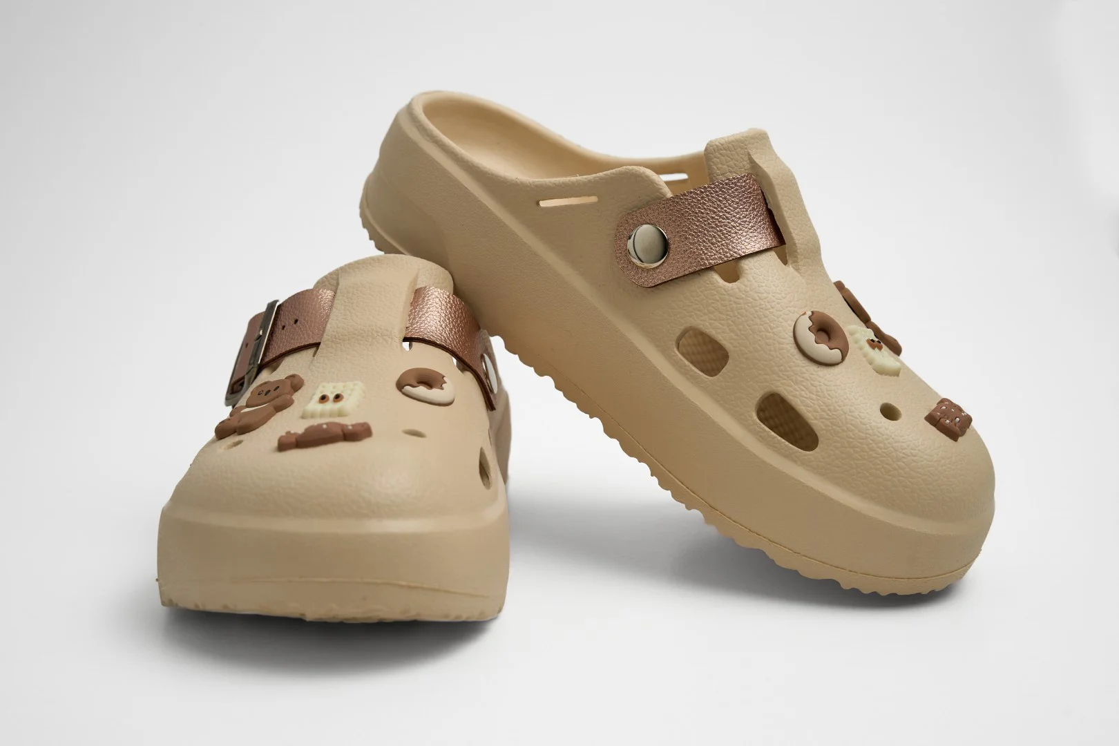 Zuecos de plataforma EVA color beige marca Concept Shoes con pines de ositos y donas sobre fondo blanco.