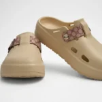 Vista frontal de par de zuecos de plataforma Concept Shoes en color beige con empeine liso y correa de patrón monograma rosa sobre fondo blanco.