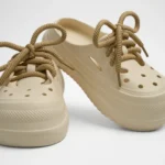 Vista frontal de par de zuecos de plataforma Concept Shoes en color hueso granulados con audaces cordones de soga café sobre fondo blanco.